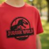 D_NQ_NP_2X_858127-MLA114408662319_072026-F Camiseta Manga Curta Malha PV Infantil Unissex Vermelha Jurassic World Silhueta Estampa Silk Screen